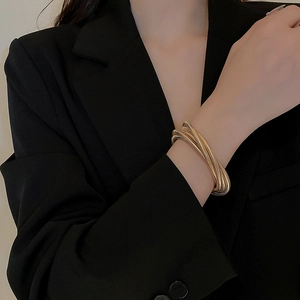 Close-up of golden multi-layer stretch bracelet on a black blazer sleeve