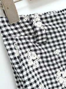 Gros plan d'un pantalon vichy noir et blanc avec broderie florale de marguerites blanches