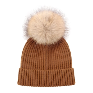 Detail of a brown ribbed knit toddler hat with a fluffy beige faux fur pom pom