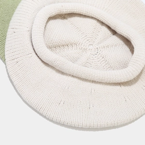Close-up of cream knit beret showing textured wool fabric and rolled edge detail