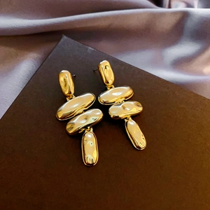 Detailed macro view of layered gold geometric dangle earrings with polished mirror finish
