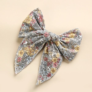 Detail of floral cotton bow hair clip with white overlock stitching and colorful patterns