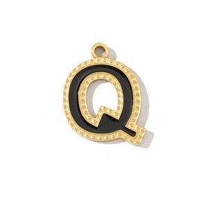 Detail of a golden stainless steel letter Q pendant with black enamel inlay and dotted edges