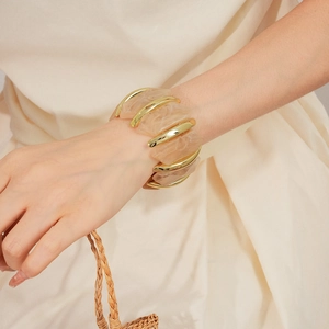 Gros plan d'un bracelet en résine marbrée et métal doré sur un poignet élégant
