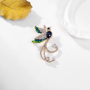 Elegant phoenix brooch with gold plating, blue enamel wings, and teardrop gemstone inlay