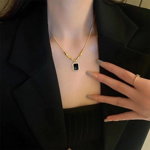 Elegant gold necklace with rectangular black pendant and matching gold ring set
