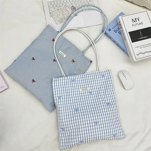Detail shot of canvas tote bags with bow embroidery and brand label on a desk