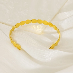 Elegant gold heart link open cuff bracelet displayed on minimalist white silk background