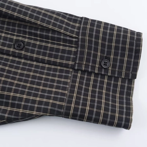 Detail of the black, gray and yellow plaid shirt cuff with buttons and fine stitching