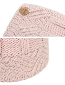 Macro view of pink chunky knit beanie showing thick diamond cable texture and brand label