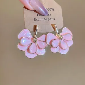 Pink layered petal earrings with gold metallic edges and crystal studs on a display card