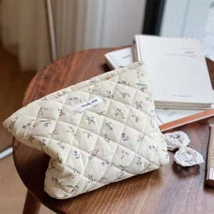 Close-up of cream quilted corduroy pouch with floral pattern and simple wish fabric label