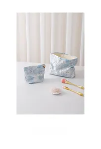 Detailed view of light blue embossed lily pattern toiletry bag set with gold zippers