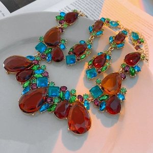 Close-up of teardrop necklace set with amber, green and purple crystals on gold