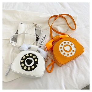 Detail of vintage telephone shaped patent leather crossbody bags in white and orange