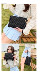 Detail of black quilted clutch bag featuring gold twist lock and elegant wrist strap
