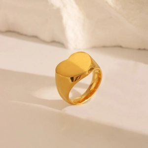 Macro shot of a golden heart-shaped signet ring with a polished minimalist stainless finish