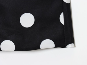Close-up of neat stitching on black and white polka dot high-waisted shorts fabric