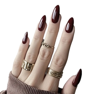 Faux ongles amande rouge foncé brillant avec bagues dorées et détail de manche