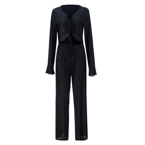 Détail d'un ensemble en maille noire montrant la texture transparente du haut et du pantalon
