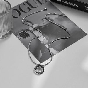 Three-interlocking rings pendant on a box chain for men, presented on a fashion magazine