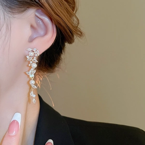 Detail view of gold tassel earrings with pearls and marquise stones on model