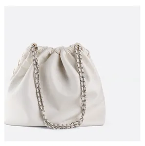 Close-up of cream white cloud tote bag with gold chain strap and drawstring detail
