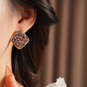 Détail d'une boucle d'oreille léopard carrée avec bordure dorée et texture en velours