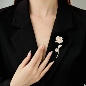 Elegant gold rose brooch with sparkling zircons and pearl on a black blazer lapel