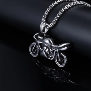 Detailed macro view of a silver punk style motorcycle pendant on a reflective black background