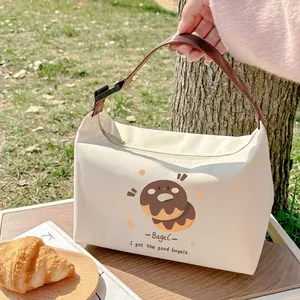 Insulated canvas lunch bag with cute bagel pattern on outdoor grass picnic setting