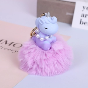 Detailed view of a purple unicorn charm with faux fur pom pom and pearl necklace detail