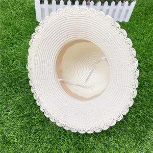 Détail du chapeau de paille crème avec bord en dentelle et corde à vent élastique blanche