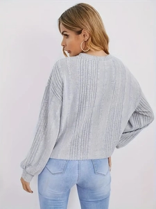Détail d'un pull en maille gris clair avec manches bouffantes et texture côtelée au dos
