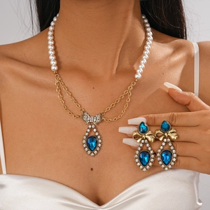 Close-up of pearl bow necklace with blue teardrop gemstone and matching earrings