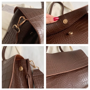 Detailed close-up of brown crocodile pattern PU leather handbag with handles and magnetic clasp