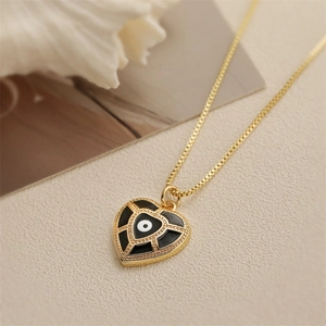 Détail du pendentif cœur doré avec motif œil et émail noir sur chaîne fine