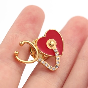 Gros plan sur la broche stéthoscope en forme de cœur avec émail rouge et strass brillants