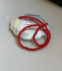 Dettaglio di una collana di perle rosse con chiusura in argento sterling 925 su vassoio conchiglia.