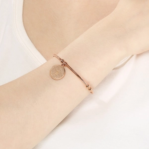Close-up of rose gold cross pendant bracelet on female wrist with minimalist style