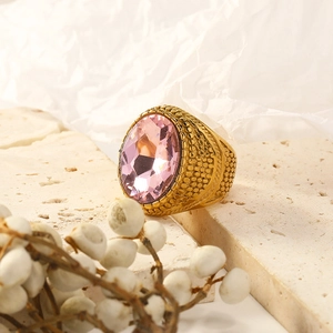 Macro detail of gold-plated punk ring with a large oval pink gemstone and textured band