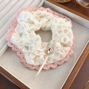 Detail of beige lace hair scrunchie with pink crochet trim and clover charm bow