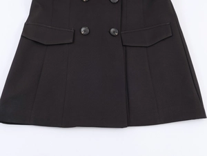 Detail of black double-breasted suit skirt featuring flap pockets and structured fabric