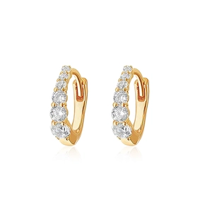 Detailed macro view of gold huggie hoop earrings featuring five graduated round zircons
