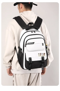 Detail of minimalist black and white backpack showing multiple zipper pockets and cartoon charm
