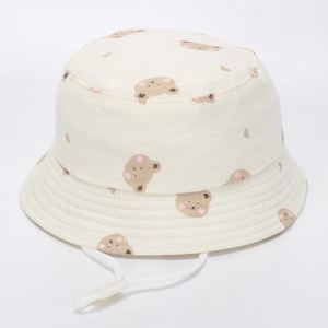 Détail d'un chapeau bob en coton blanc avec motifs d'ours et jugulaire réglable