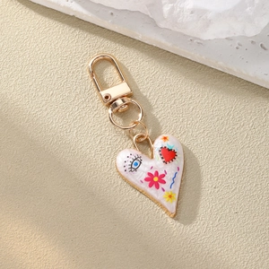 Close-up of golden heart keychain with colorful enamel evil eye and floral patterns