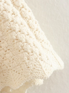 Dettaglio ravvicinato della trama del tessuto a maglia all'uncinetto bianco crema e finiture