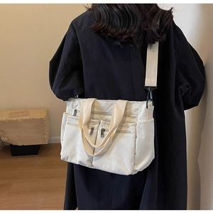 Close-up of white corduroy shoulder bag with multiple zippers and adjustable strap