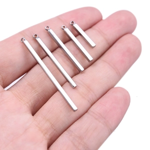 Macro shot of five silver stainless steel bar pendants held by hand for size reference